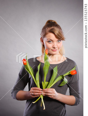 Blonde woman with single tulip. Blonde woman with single tulip. 135523743