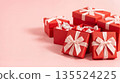 Red gift boxes arranged on a pink background for a celebration or special occasion with ribbons and decorative paper 135524225
