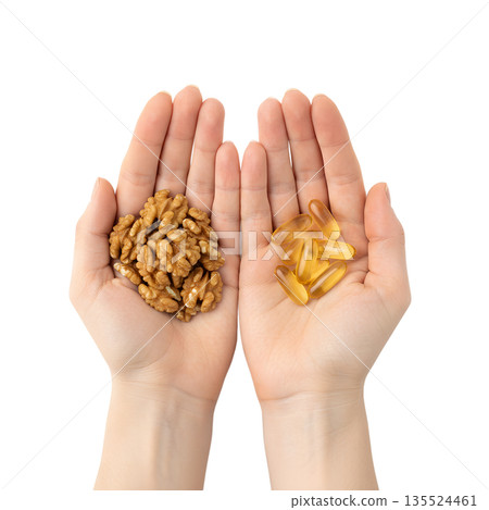 Nutrition comparison, handful of whole walnuts next to omega-3 supplement capsules, isolated. Represents natural ALA sources vs. supplements Nutrition comparison, handful of whole walnuts next to omega-3 supplement capsules, isolated. Represents natural ALA sources vs. supplements 135524461