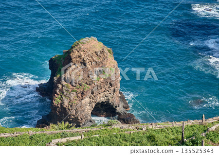 Geological formation of Roque Grande emerging from the blue sea at Los Roques Beach in Tenerife Geological formation of Roque Grande emerging from the blue sea at Los Roques Beach in Tenerife 135525343