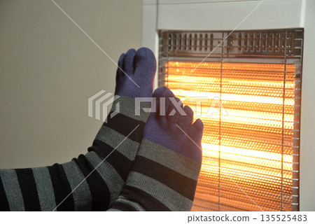 An old man's feet warmed by an electric heater 135525483