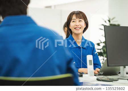 A young woman in work clothes doing desk work in the office 135525602