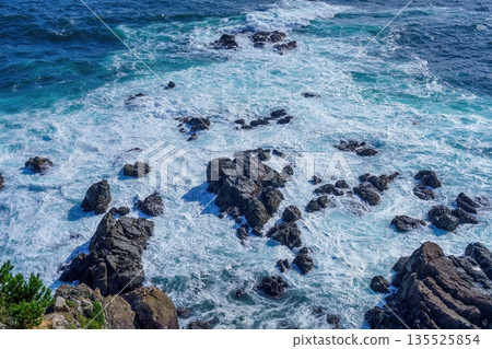 鈷藍色的海水和洶湧的白色巨浪拍打著礁石。 135525854