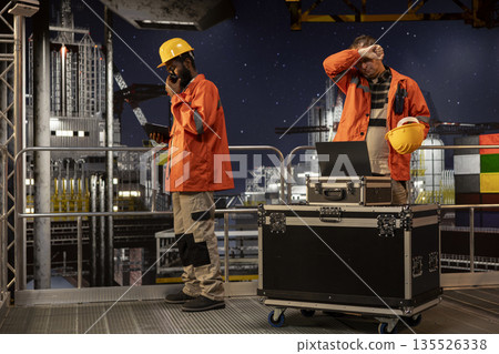 Concerned employee on offshore oil platform manages petroleum extraction using laptop, sweating and struggling to ensure safe oil extraction. Worried restless engineer in tension. Concerned employee on offshore oil platform manages petroleum extraction using laptop, sweating and struggling to ensure safe oil extraction. Worried restless engineer in tension. 135526338