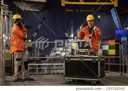 Frustrated offshore engineer about oil extraction activity on platform, worried about environmental impact, anxious expert handling petroleum evaluation on laptop. Sweating employee. 135526342