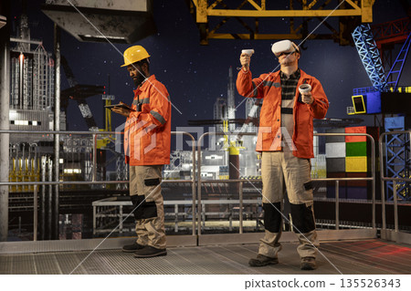 Male employee with VR glasses on offshore oil platform uses virtual reality tech to simulate drilling operations and monitor machinery, ensuring safety protocols in petroleum extraction. Male employee with VR glasses on offshore oil platform uses virtual reality tech to simulate drilling operations and monitor machinery, ensuring safety protocols in petroleum extraction. 135526343