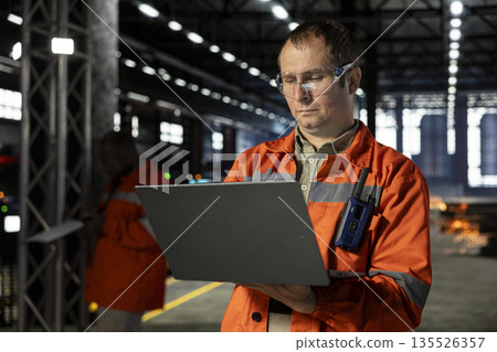 Industrial personnel inspects steel equipment on factory floor in protective gear, demonstrating engineering skill for the steel manufacturing process. Power of workforce operation. Industrial personnel inspects steel equipment on factory floor in protective gear, demonstrating engineering skill for the steel manufacturing process. Power of workforce operation. 135526357