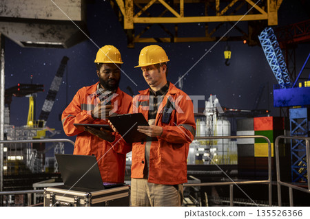 Environmental officers communicating via radio on marine oil platform, assessing extraction data, control and maintain balance of natural fuel and petroleum from the ocean ecosystem. Environmental officers communicating via radio on marine oil platform, assessing extraction data, control and maintain balance of natural fuel and petroleum from the ocean ecosystem. 135526366