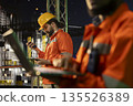 Close up of industrial drilling ship specialist inspecting infrastructure integrity using laptop. Offshore platform colleagues performing machinery checkup to ensure safety during nighttime operations 135526389