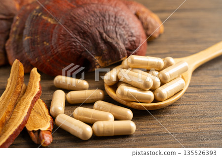 Dried lingzhi mushroom with capsule drug, alternative medicine herbal organic herb. Dried lingzhi mushroom with capsule drug, alternative medicine herbal organic herb. 135526393