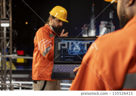 Drilling barge specialist analyzing gear performance on laptop using artificial intelligence. Offshore platform worker monitoring oil extraction rates and system pressure using AI machine learning 135526415