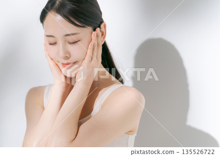 A woman cupping her cheeks with both hands A woman cupping her cheeks with both hands 135526722