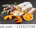 Traditional sliced Christmas stollen loaf with raisins and powdered sugar on wooden cutting board 135527194