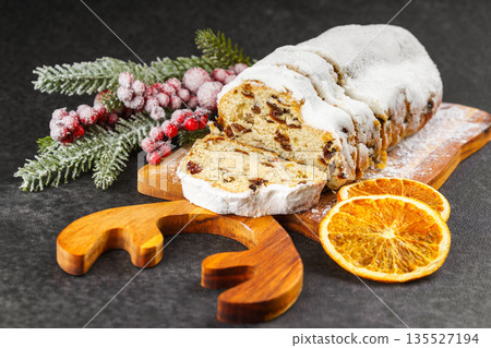 Traditional sliced Christmas stollen loaf with raisins and powdered sugar on wooden cutting board Traditional sliced Christmas stollen loaf with raisins and powdered sugar on wooden cutting board 135527194