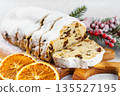 Traditional sliced Christmas stollen loaf with raisins and powdered sugar on wooden cutting board 135527195