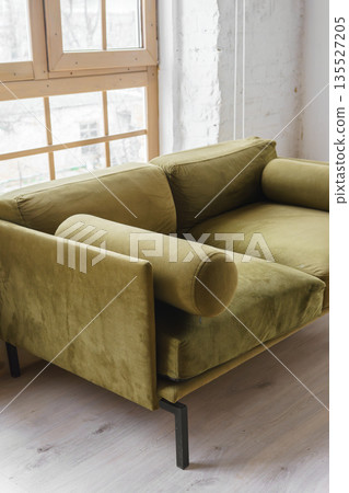 Modern khaki green velvet sofa near large window in stylish living room, loft interior 135527205