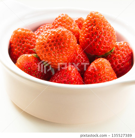 Fresh red strawberries in a white cup on a white background Fresh red strawberries in a white cup on a white background 135527389