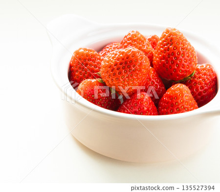 Fresh red strawberries in a white cup on a white background Fresh red strawberries in a white cup on a white background 135527394