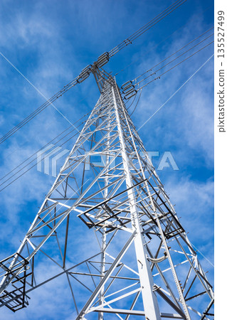 Looking up at the high-voltage power transmission tower, clear sky and clouds a-1 135527499