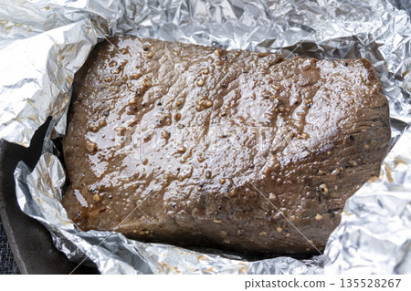 烤牛肉烹飪場景。包裹牛肉的鋁箔被打開。 135528267