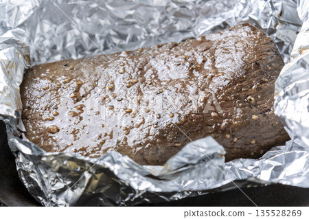 Roast beef cooking scene. The aluminum foil that was wrapping the beef is opened. Roast beef cooking scene. The aluminum foil that was wrapping the beef is opened. 135528269