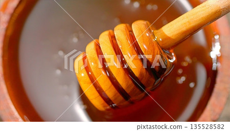 Rustic Kitchen Scene With Thick Honey Streaming Into Ceramic Dish Illuminated By Soft Morning Light Rustic Kitchen Scene With Thick Honey Streaming Into Ceramic Dish Illuminated By Soft Morning Light 135528582