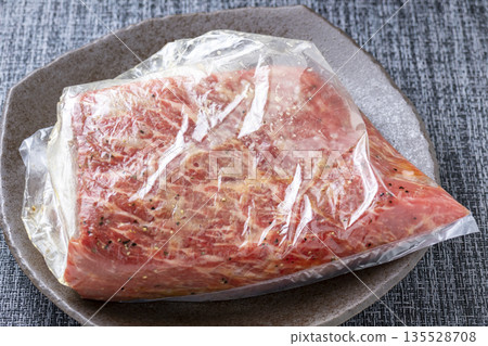 Roast beef cooking scene. The beef block and seasonings are placed in a plastic bag and seasoned. Roast beef cooking scene. The beef block and seasonings are placed in a plastic bag and seasoned. 135528708