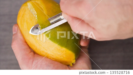 Closeup Of Peeling Ripe Mango With Peeler, Home Cook Slicing Bright Mango On Countertop With Focus Closeup Of Peeling Ripe Mango With Peeler, Home Cook Slicing Bright Mango On Countertop With Focus 135528716