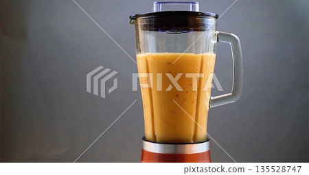 Colorful Drink Preparation, Vivid Mango Blend In Glass Jar With Sleek Metal Base And Calm Grey Background 135528747