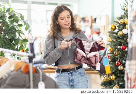 Girl interesting goods, scans QR code and label of lingerie, X mas shopping Girl interesting goods, scans QR code and label of lingerie, X mas shopping 135529295