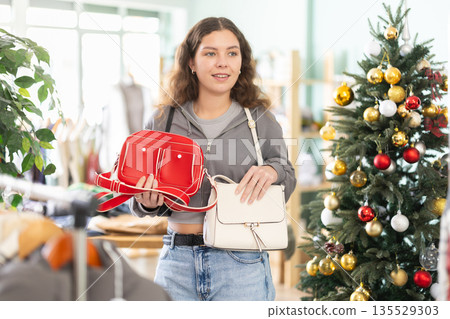 Young woman choosing handbag in clothing store Young woman choosing handbag in clothing store 135529303