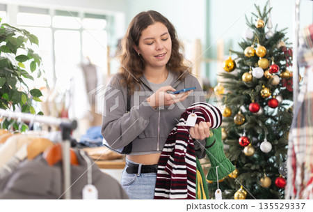 Young woman scanning qr code for sweater in store 135529337