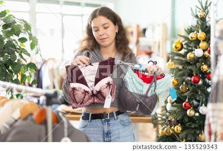 Young woman chooses lingerie in clothing store Young woman chooses lingerie in clothing store 135529343