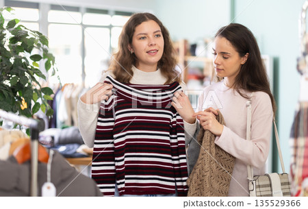 Two women choosing a knitted sweater in a store 135529366