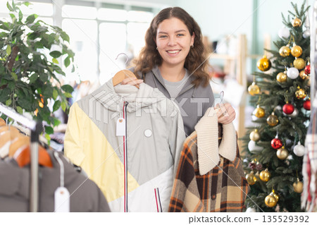 Young girl choosing coat or jacket in clothing store during Christmas 135529392