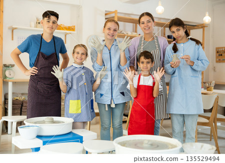 Happy children posing female teacher in pottery workshop 135529494