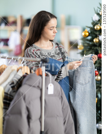 woman chooses high quality jeans against the background of a Christmas tree woman chooses high quality jeans against the background of a Christmas tree 135529560