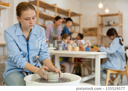 Teenage girl working at potter's wheel 135529577
