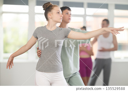 Teenage girl practicing ballet positions in pair with boy in dance studio 135529588
