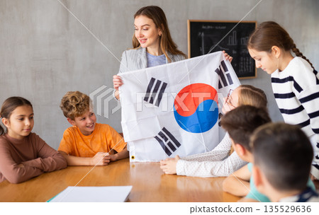 Teacher showing flag of South Korea to group of schoolchildren Teacher showing flag of South Korea to group of schoolchildren 135529636