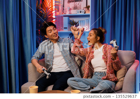 Couple gamer raising fist up holding joysticks be winner together. Infobahn. Couple gamer raising fist up holding joysticks be winner together. Infobahn. 135529637