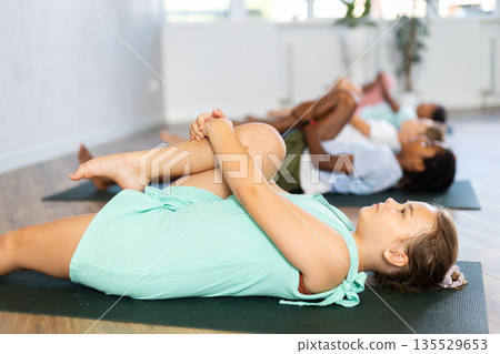 Young girl doing pilates in group of children Young girl doing pilates in group of children 135529653