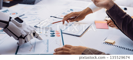 Collaborative Work Environment with Human and Robot Hands Analyzing Business Charts and Graphs, Displaying Technology Integration in Modern Offices. Noogenesis 135529674