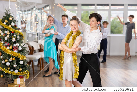 Teen boy and girl dancing waltz in couple during lesson at studio in New Year atmosphere 135529681