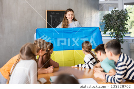 Teacher showing Ukraine flag to group of schoolchildren Teacher showing Ukraine flag to group of schoolchildren 135529702