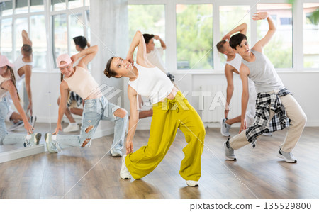 Teenage girl practicing hip-hop backbend moves in training hall 135529800