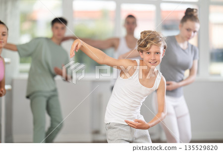 Young boy in group lesson with students rehearses, practices ballet dance, staging. Young boy in group lesson with students rehearses, practices ballet dance, staging. 135529820
