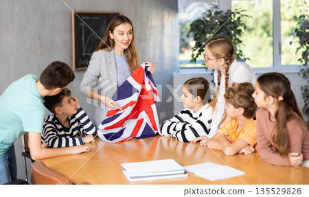 Teacher talking about country and national flag of the Great Britain at Geography lesson. Positive Schoolchildren and female teacher discussing Teacher talking about country and national flag of the Great Britain at Geography lesson. Positive Schoolchildren and female teacher discussing 135529826