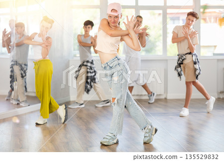 Teenage girl practicing basic hip hop moves in training hall Teenage girl practicing basic hip hop moves in training hall 135529832