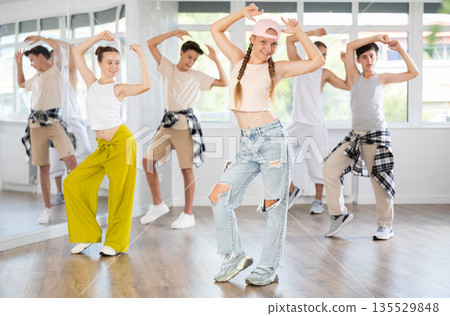 Active teenagers practicing hip hop dance in training hall during group dancing classes Active teenagers practicing hip hop dance in training hall during group dancing classes 135529848
